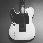 a white left handed telecaster electric guitar with black pickups & pick guard.