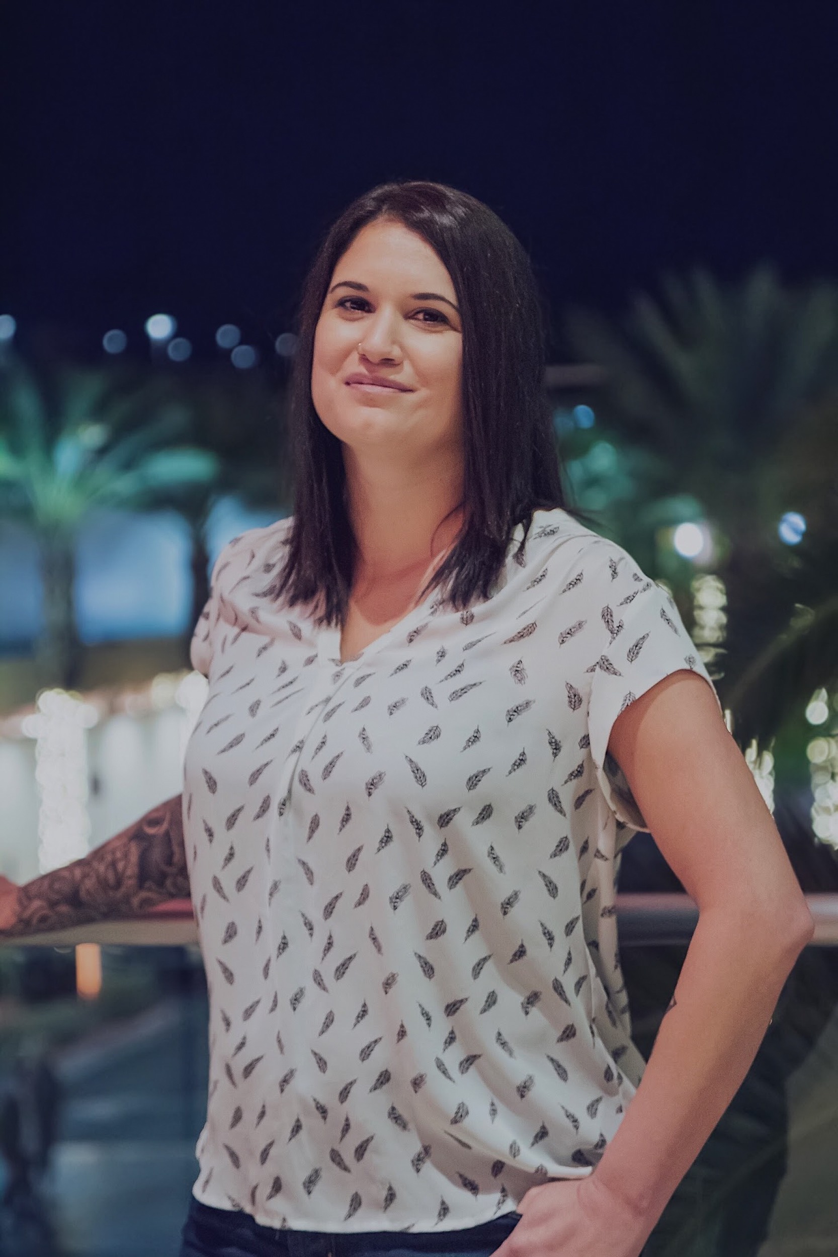 a woman with a tattoo in front of some palm trees at night