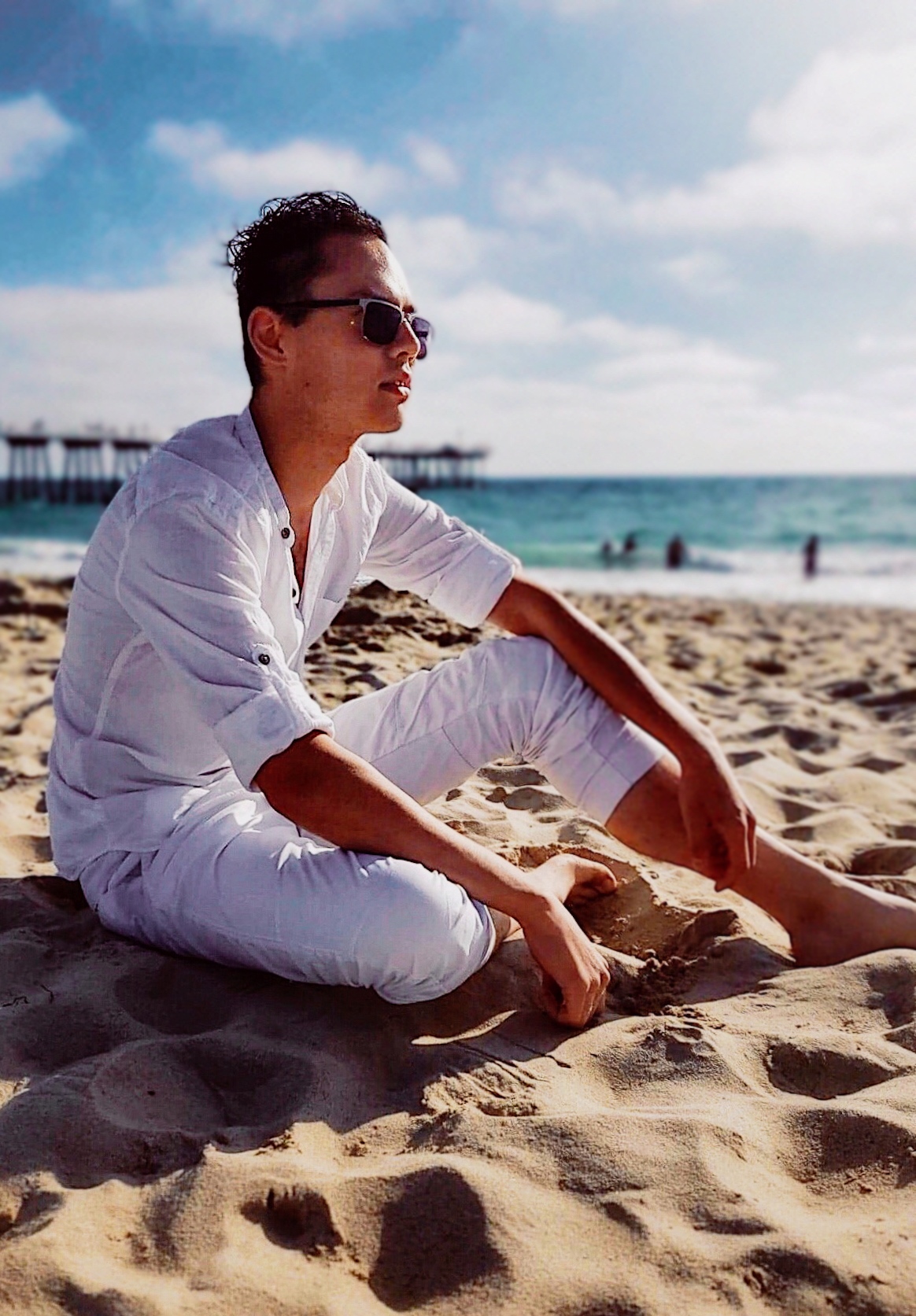 a man in white sitting on a beach edited by flashqbe.