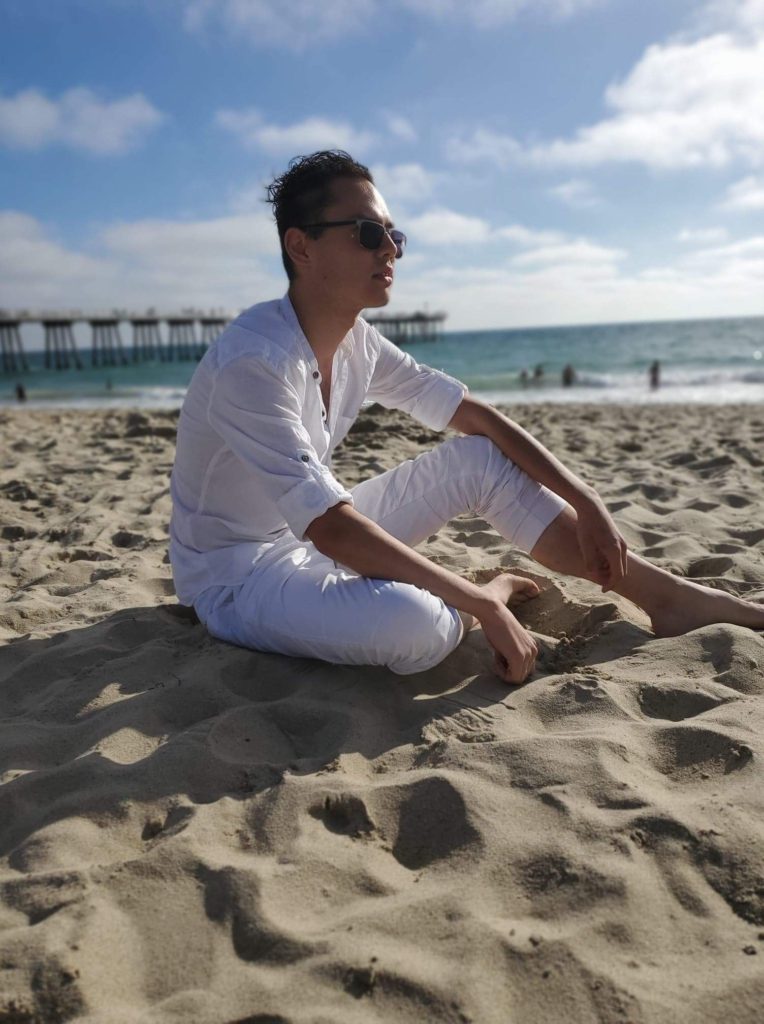 man on a beach in white with sunglasses before flashqbe edit