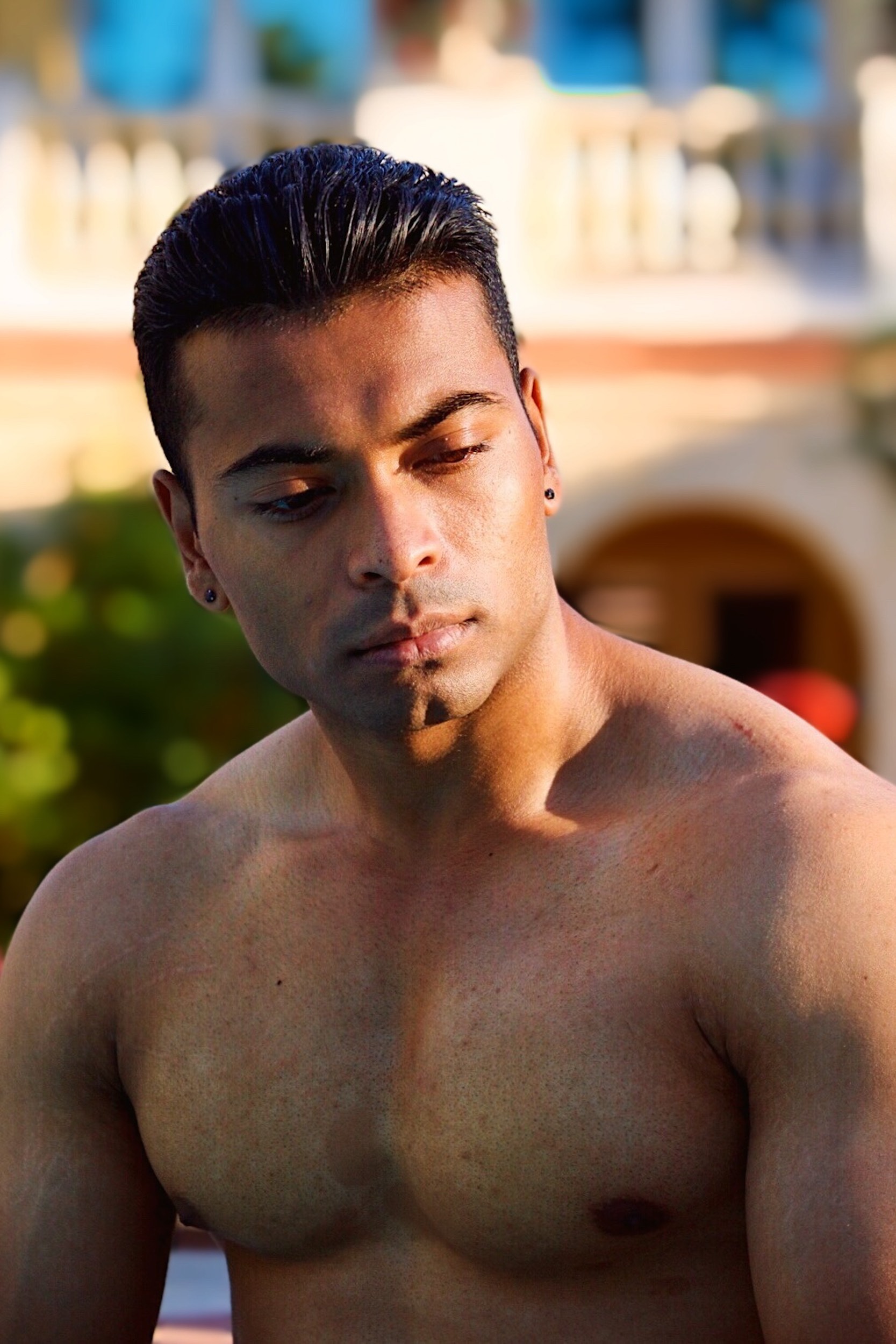 closeup of man sitting next to swimming pool in the sunlight.