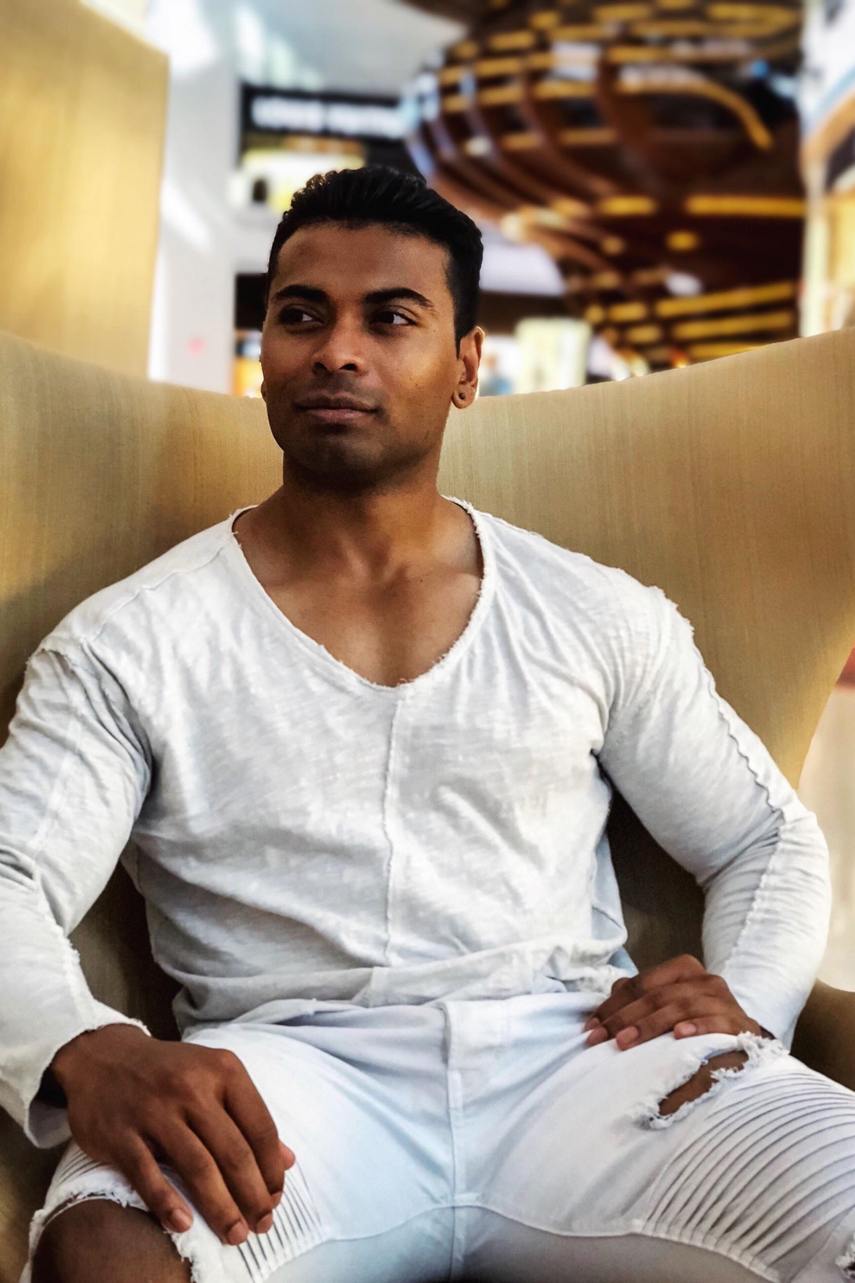 a relaxed man in all white sitting in a chair looking away from the camera.