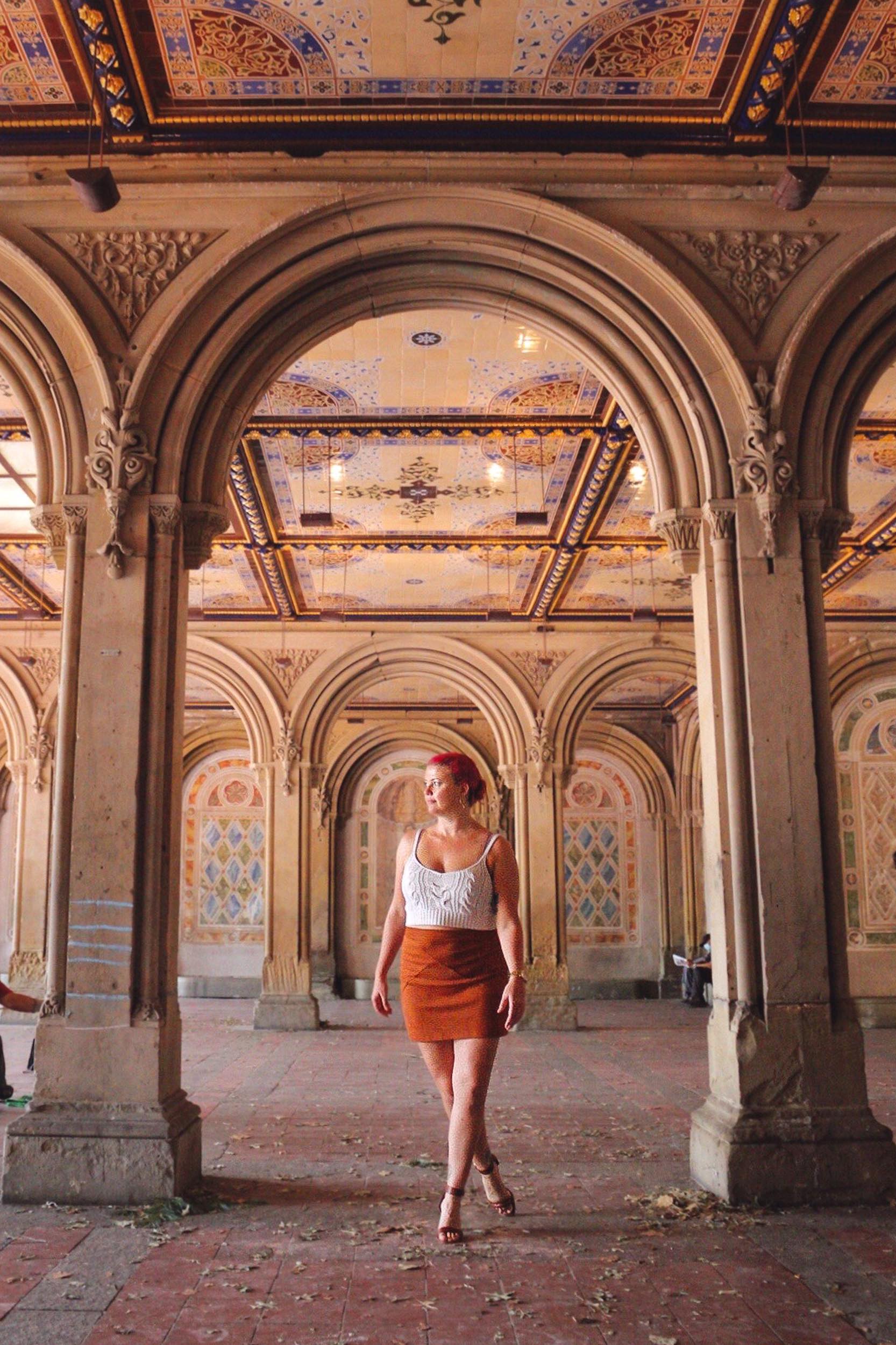 a woman in rust colored skirt standing in central park.