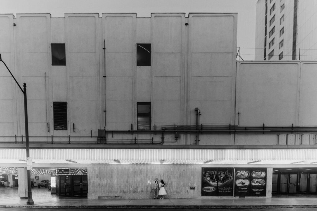 Retro Vegas elopement couple under glowing marquee in black and white
