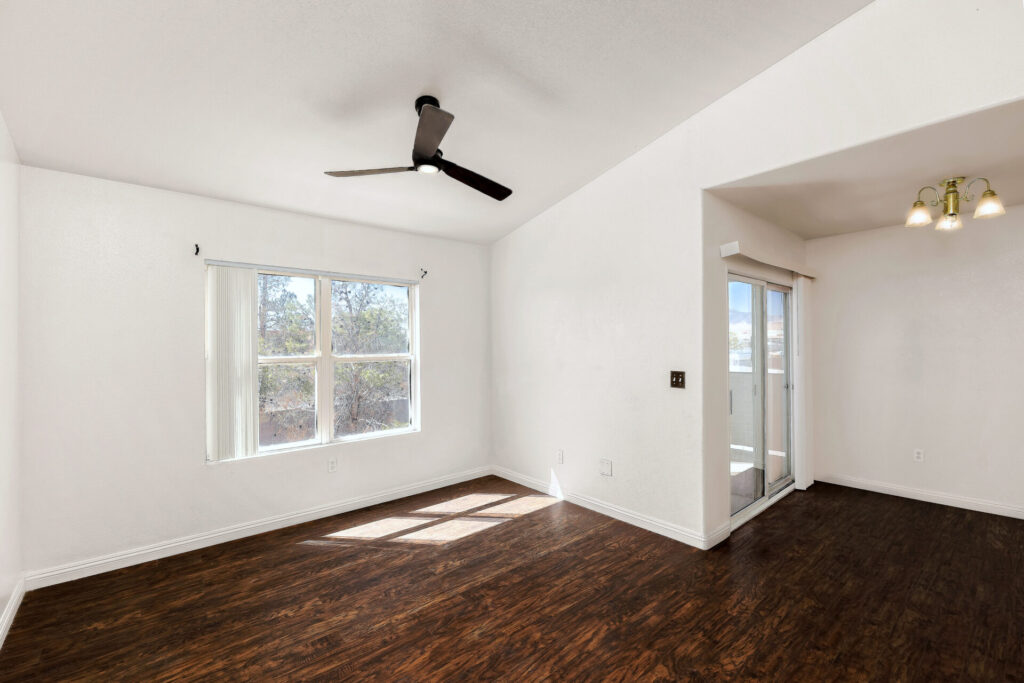 An empty condo with vaulted ceilings, white walls & dark wood floors, showing pro photography’s benefits: sharp & well lit.
