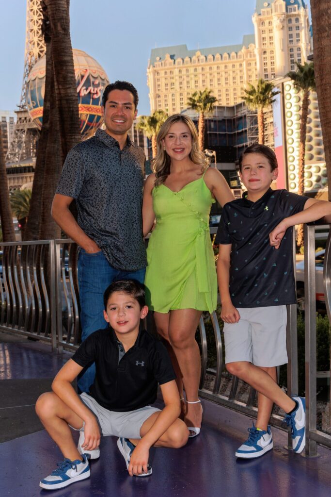 A family of four posing together on the Las Vegas Strip with the Paris Hotel and palm trees in the background during a professional photo session.