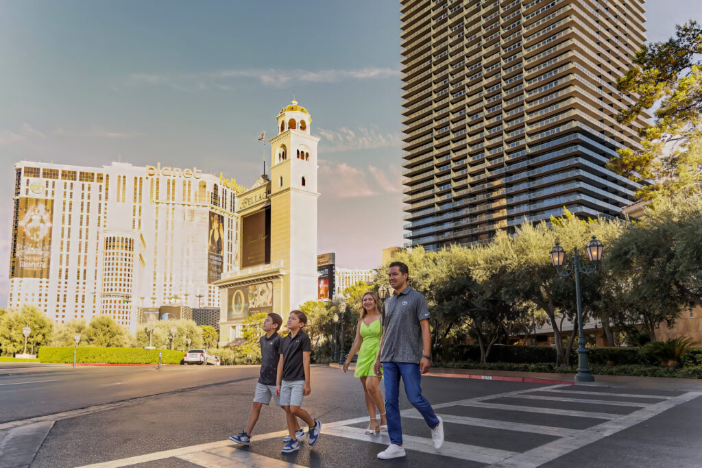 A family of four walking across a crosswalk on the Las Vegas Strip with tall hotels and billboards in the background during a professional photography session.